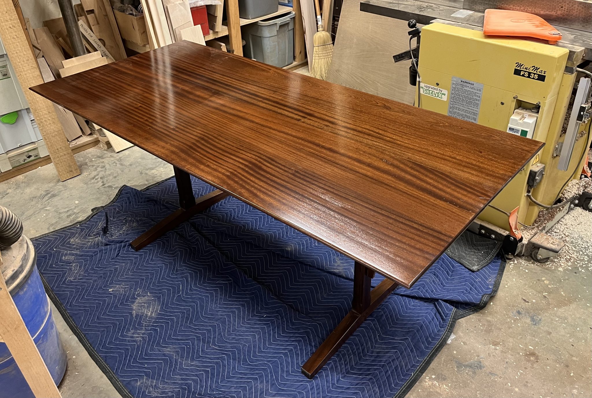 Trestle type dining room table in Sapele with lacquer finish